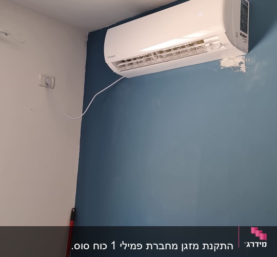 מזגן מותקן על קיר כחול עם כבל חשמל לבן